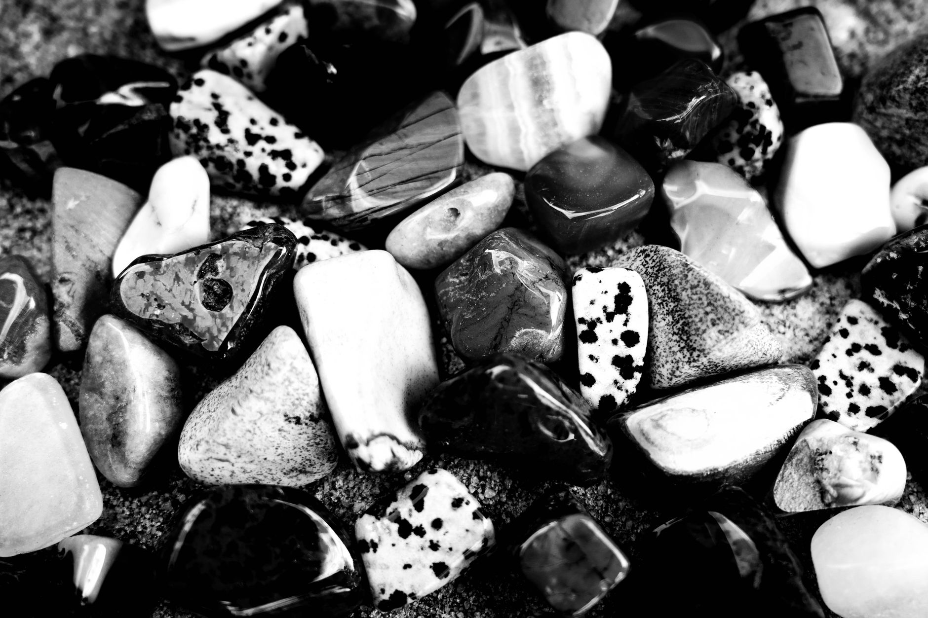 two black rubber rock tumbler barrels sitting beside polished agate stones on a table