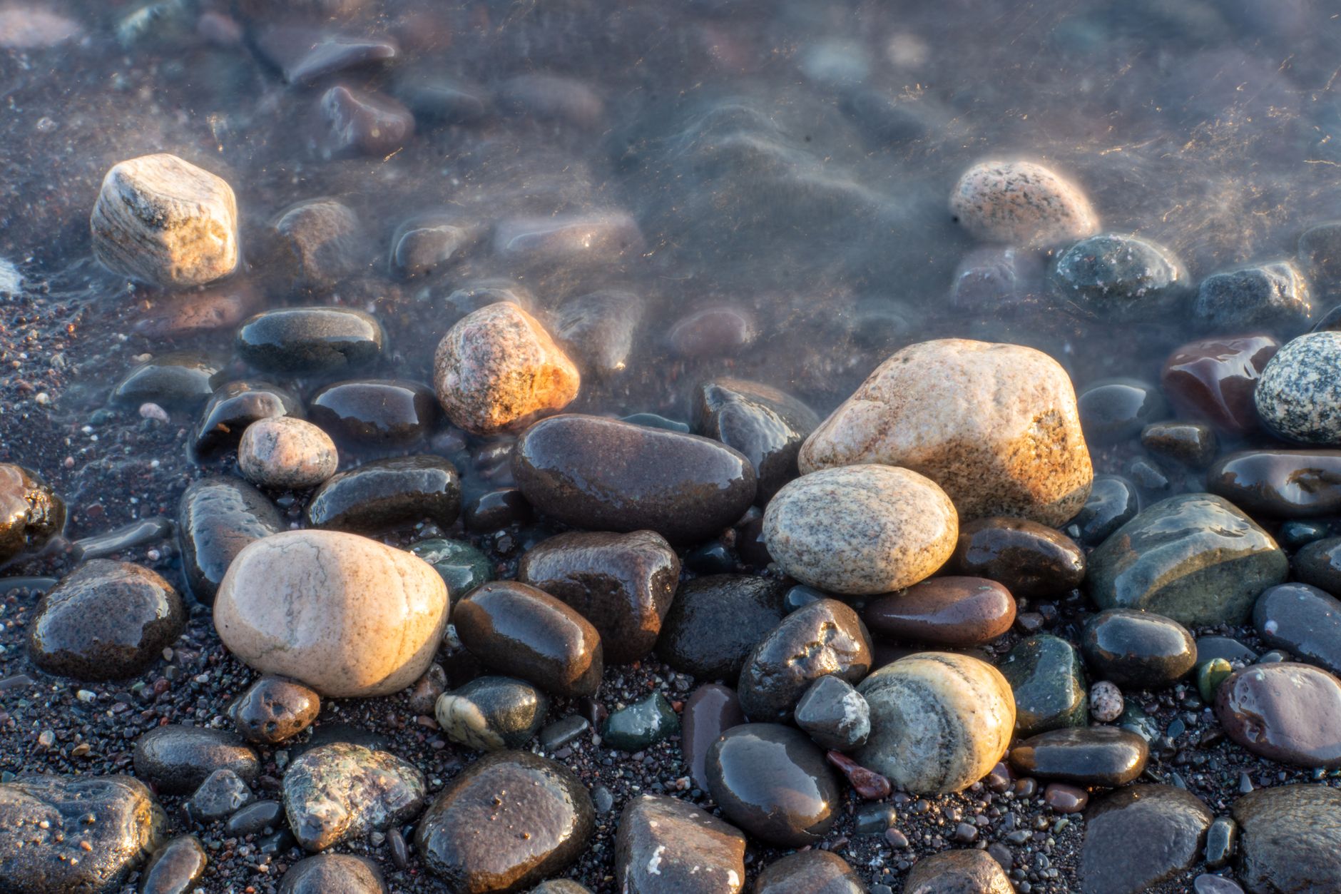 banded Lake Superior agate stones on a pebble beach with lake water